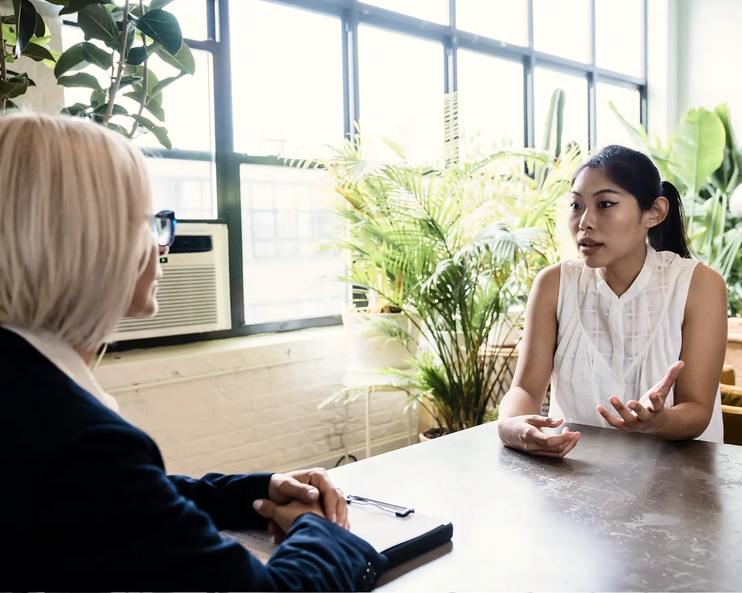 Funding advisor talking through options with a business owner in a bright office full of plants