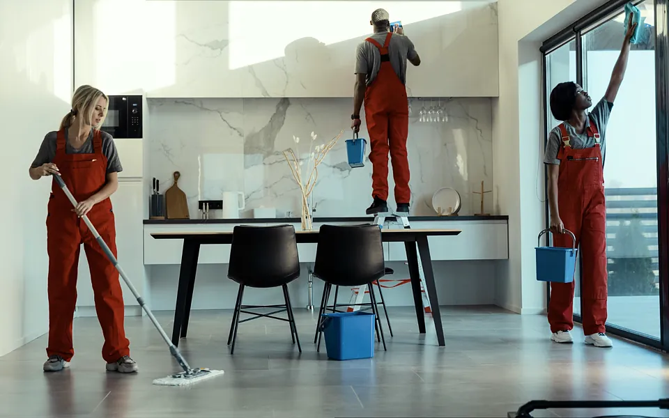 Cleaning crew in work overalls mopping floors and wiping windows in a bright space