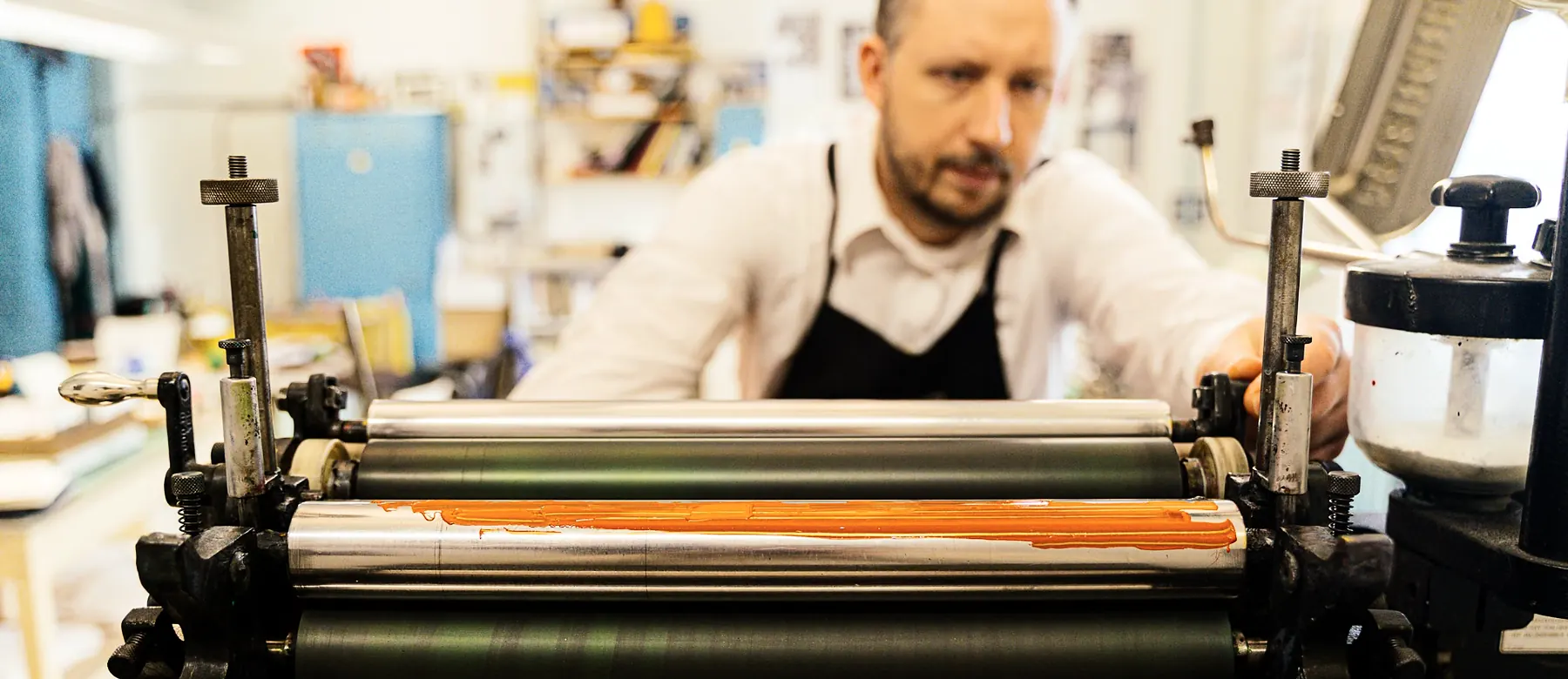 Press operator adjusting the inking rollers of a printing press