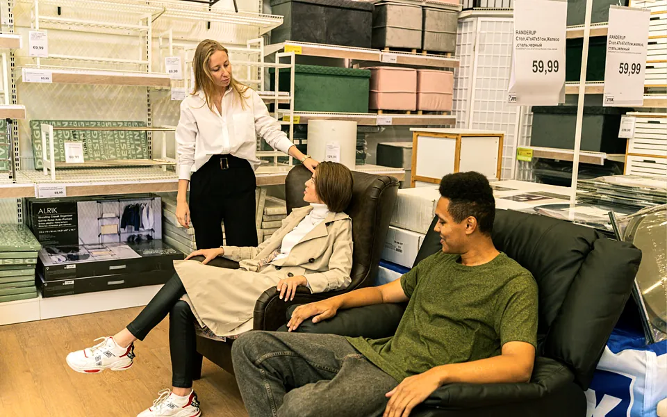 Salesperson helping customers try a sofa in a furniture showroom