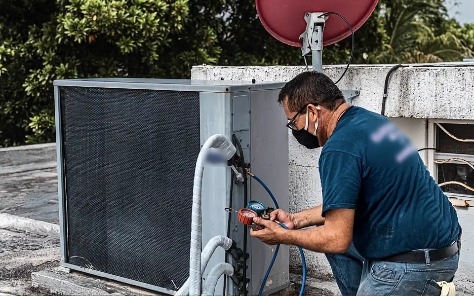HVAC technician checking refrigerant pressure on an outdoor condenser unit