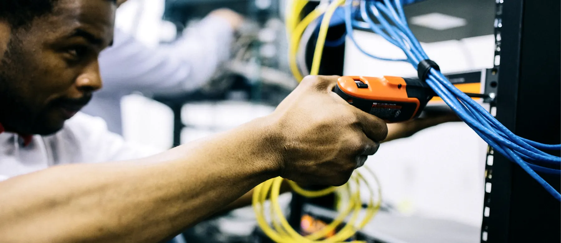 IT technician connecting network cables in a server rack