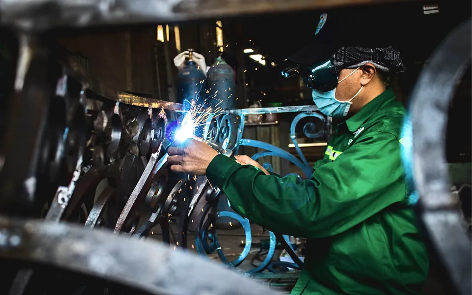 Welder in protective gear fabricating a steel railing