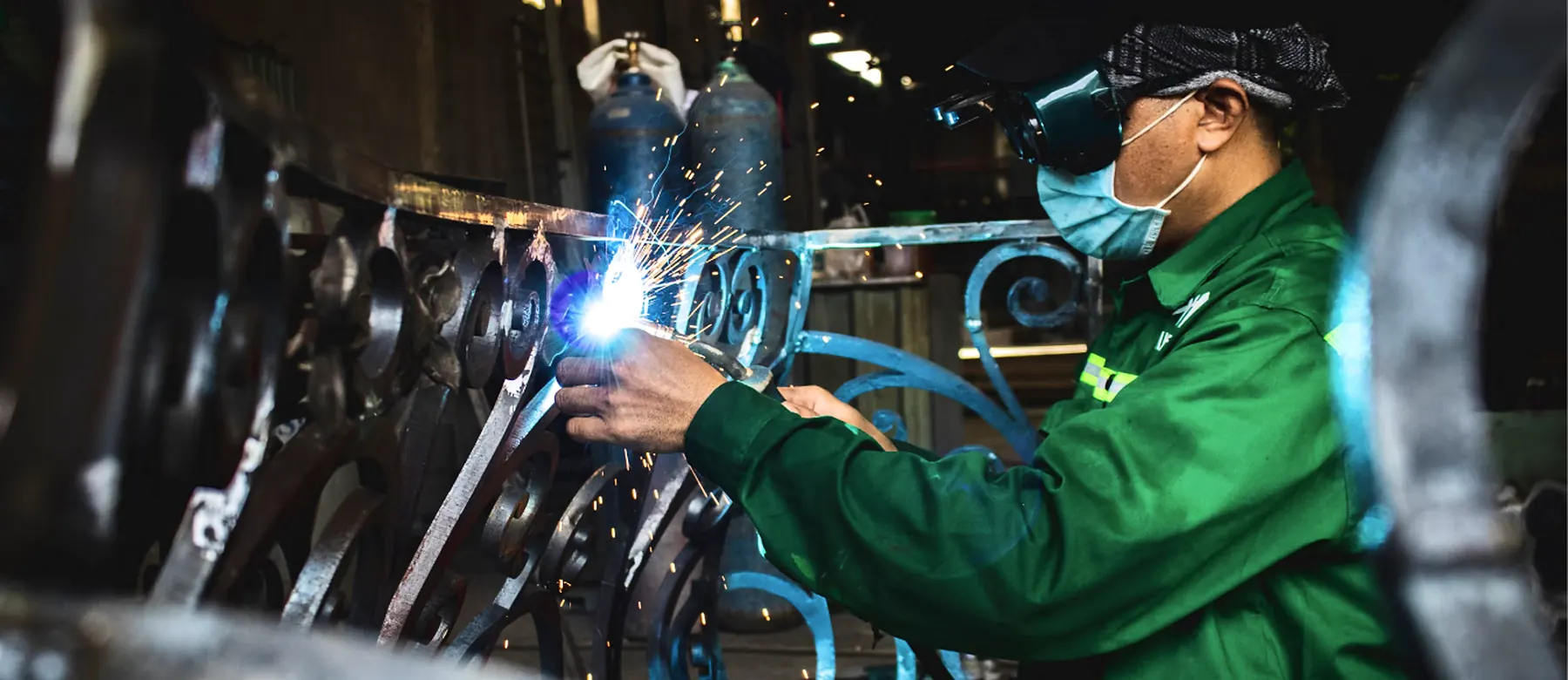 Welder in protective gear fabricating a steel railing