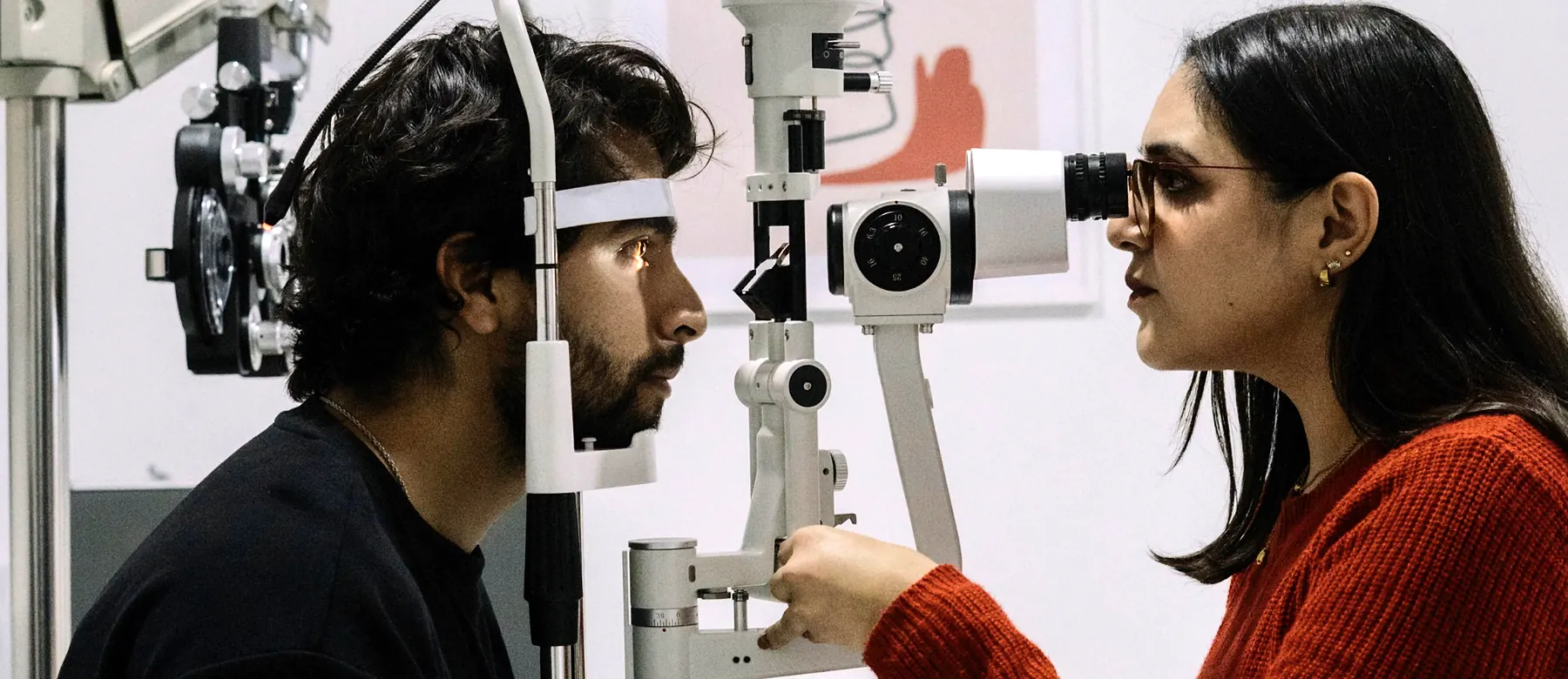 Optometrist examining a patient with a slit lamp in an exam room