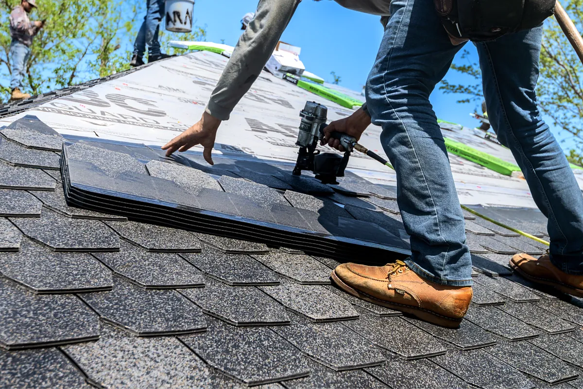 Roofer nailing asphalt shingles on a residential roof