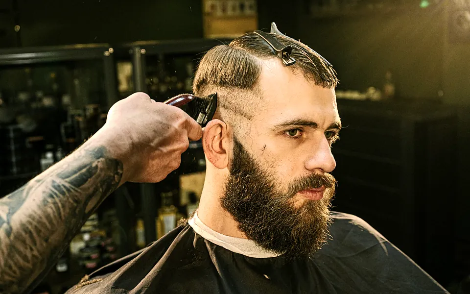 Barber trimming a client’s hair with clippers in a barbershop