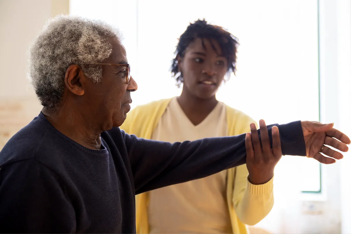 Caregiver helping an older man with an arm exercise