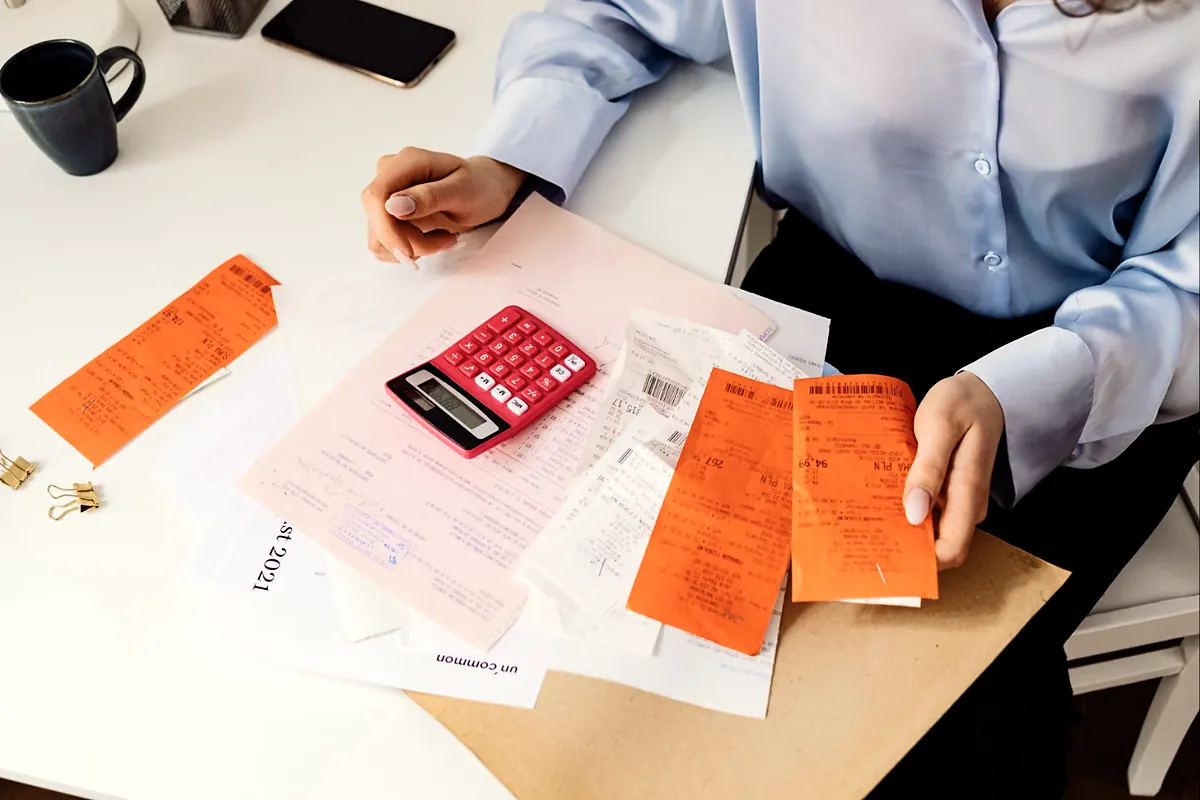 Business owner sorting receipts beside a calculator