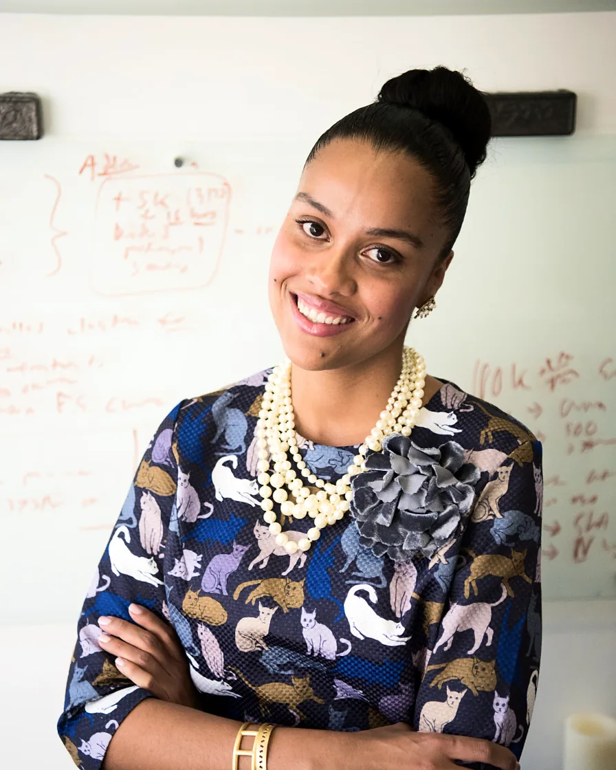 Smiling business owner standing with arms crossed in her office