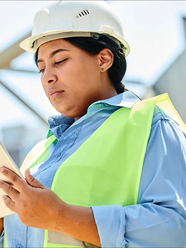 Construction contractor in a hard hat reviewing plans on a tablet
