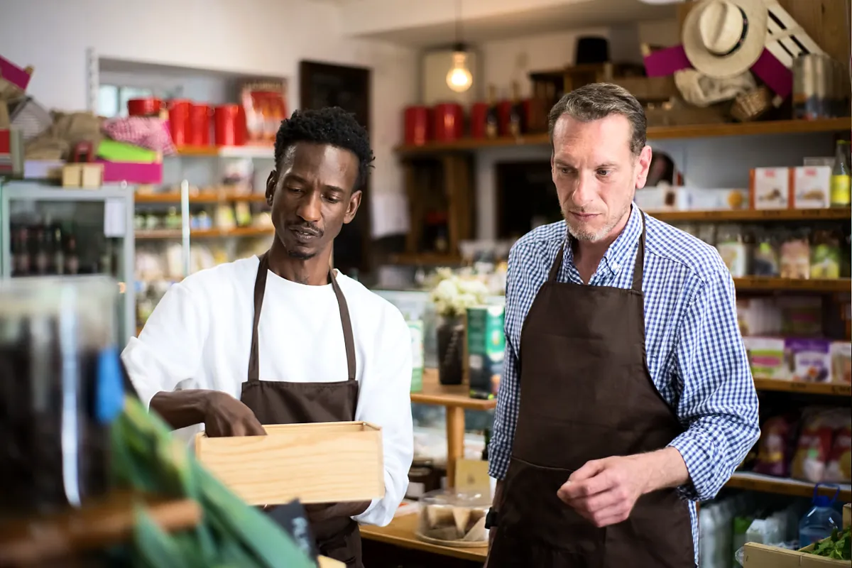 Two shop owners in aprons sorting products together in their store
