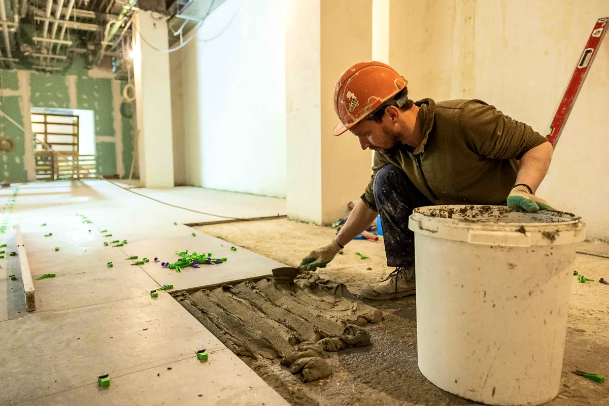 Contractor laying floor tile during a commercial space renovation
